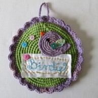It's a crochet picture with buttons and a lilac birdie.